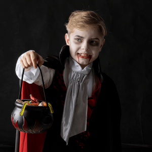 Classic vampire outfit on young boy with trick or treat pot